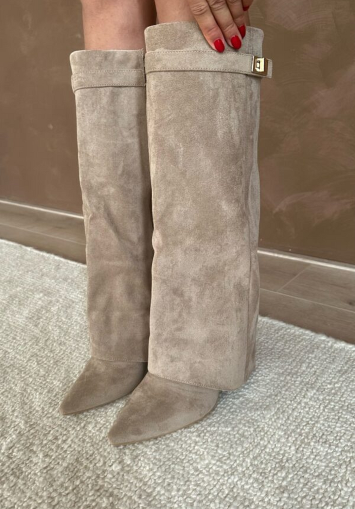 Bottes beige taupe effet daim à bout pointu, coupe mi-mollet avec revers et boucle dorée, portées debout sur tapis.
