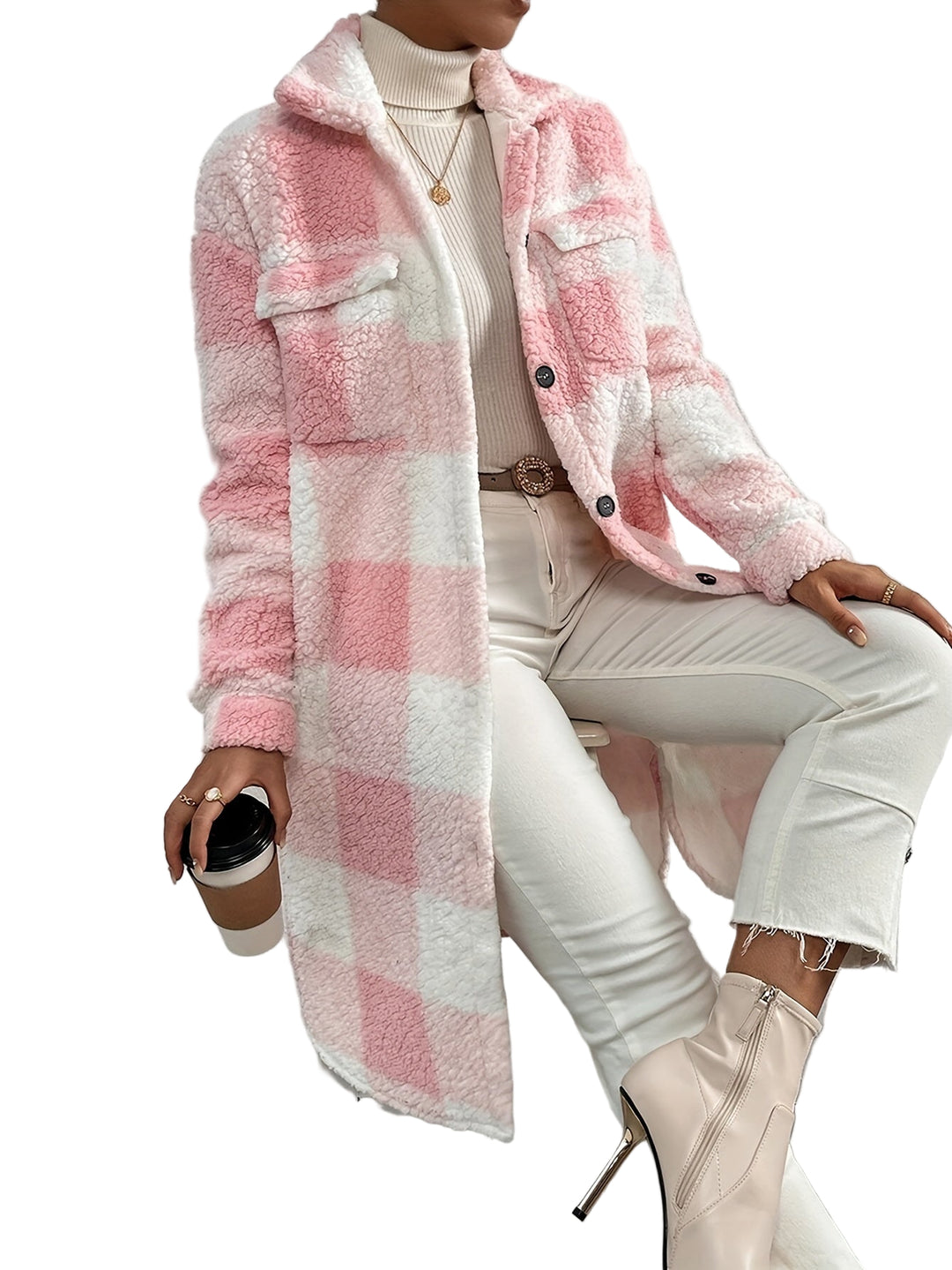 Une femme porte un manteau à carreaux rose et blanc en peluche avec des manches longues. Le manteau présente un col classique et des poches avant à rabat. Elle le porte avec un turtleneck beige, un pantalon blanc et des bottines à talons, créant une tenue élégante et confortable. Elle tient un café à la main, assise sur une chaise dans un intérieur moderne.