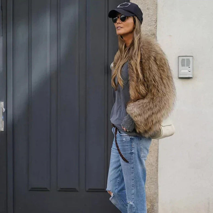 Tenue de rue tendance : femme en veste en fourrure synthétique, jean ample et accessoires noirs.