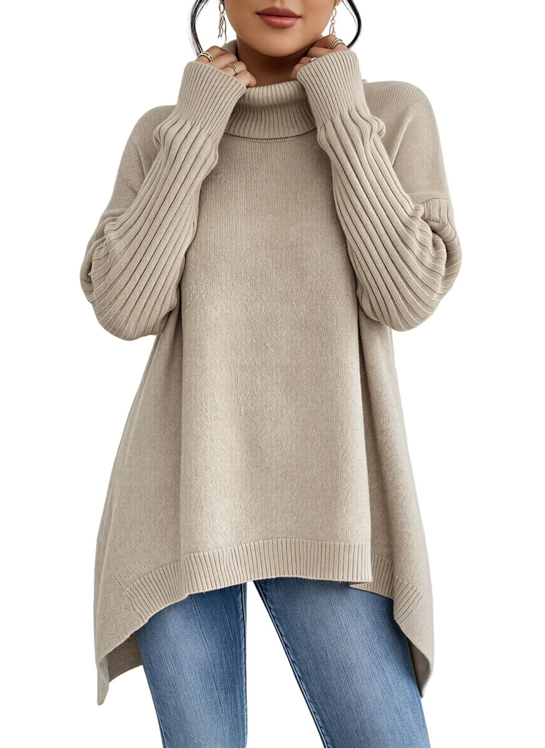 Une femme porte un pull à col roulé beige ample à manches longues côtelées. Ce haut fluide et légèrement asymétrique est associé à un jean bleu pour un look élégant, moderne et confortable, idéal pour l'automne/hiver.