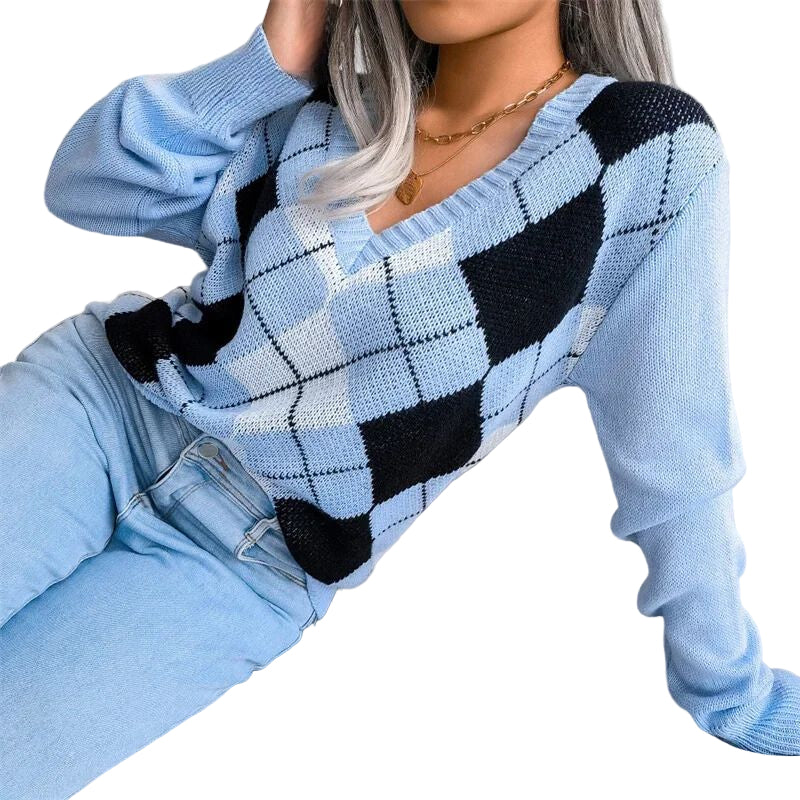 Une femme porte un pull à col en V en maille douce, orné d’un motif à losanges de style argyle dans les tons bleu clair, noir et blanc. Le pull présente une coupe décontractée avec des manches longues et des bords côtelés, associé à un jean bleu clair. L’ensemble dégage un style moderne et confortable, idéal pour les journées d’hiver.