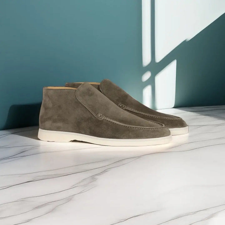 Mocassins pour homme en suédine gris taupe, au design moderne et minimaliste avec semelle claire, idéals pour un style élégant et polyvalent.