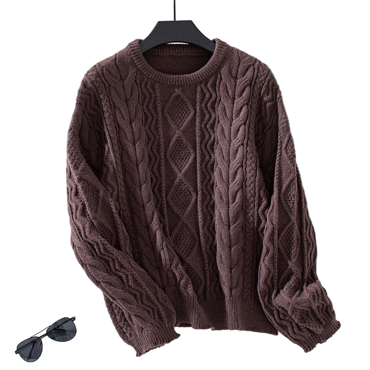 Pull en maille torsadée de couleur marron chocolat, au motif géométrique en losanges sur le devant. Le tissu épais et texturé met en avant des torsades élégantes et un tricot dense, parfait pour un style chaud et confortable. Présenté sur un cintre noir contre un fond blanc lumineux, le pull se distingue par ses manches longues légèrement bouffantes et ses finitions côtelées au col, aux poignets et à la taille. Une paire de lunettes de soleil posée à côté apporte une touche moderne à la mise en scène.