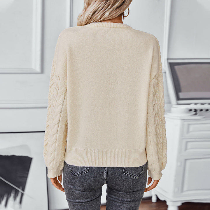 Vue de dos d'une femme portant un pull blanc à manches longues en maille torsadée. Le dos du vêtement est lisse, contrastant avec la texture des manches. La maille, à la coupe droite et aux bords-côtes, offre un style à la fois simple et élégant. Le pull est associé à un jean foncé, créant une allure moderne et décontractée dans un intérieur lumineux et raffiné.