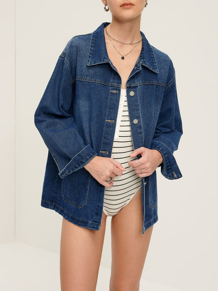 Modèle féminin portant la veste en jean 'Sylpha', une veste décontractée en denim bleu, à la coupe ample et moderne. La veste est agrémentée de boutons argentés et de poches avant pratiques, créant un look tendance et élégant.