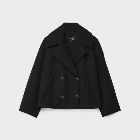 Manteau court noir à double boutonnage, col large façon tailleur et coupe ample, présenté sur fond clair.