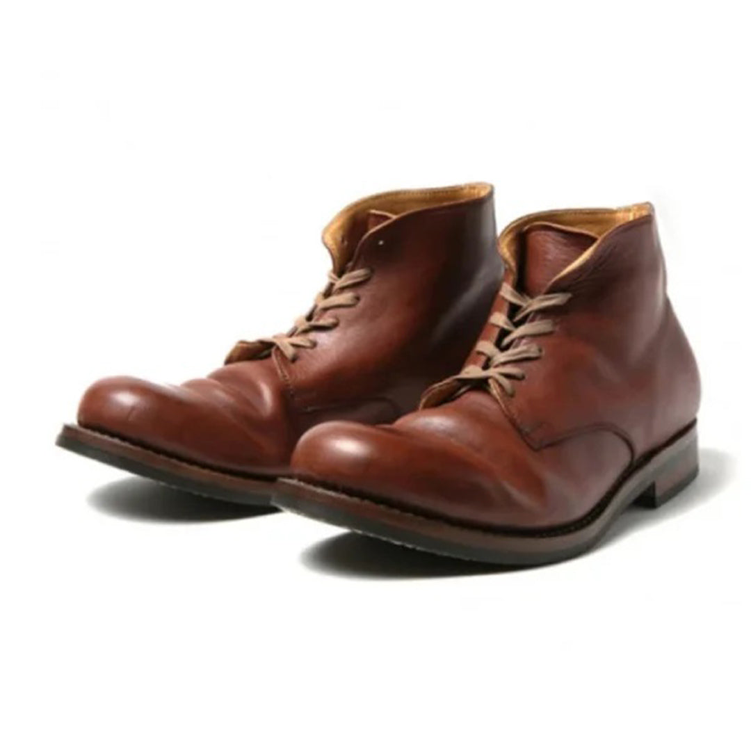 Paire de bottes en cuir marron pour homme au design intemporel, dotées de lacets beiges et d’une doublure intérieure en cuir clair. Leur finition brillante et leur coupe montante offrent une allure élégante et durable, parfaite pour un usage quotidien ou professionnel. Présentées sur fond blanc pour mettre en valeur la texture et la qualité artisanale du cuir.