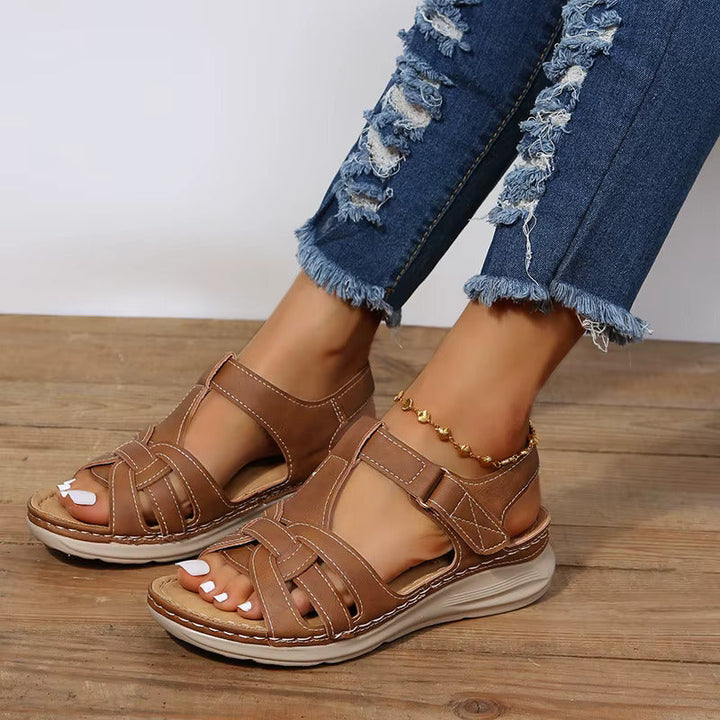 Modernes, coloris camel avec surpiqûres claires, brides ajourées et semelle confort épaisse, portées avec un jean sur sol en bois.