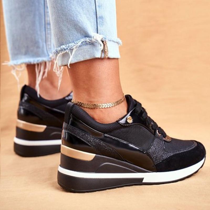 Vue rapprochée d’une paire de baskets modernes pour femme en noir et doré, avec une semelle épaisse blanche et noire. Les chaussures présentent un design élégant avec des empiècements métallisés et des lacets noirs. Elles sont portées avec un jean retroussé et un bracelet de cheville doré, créant un look tendance et confortable pour un style urbain chic.