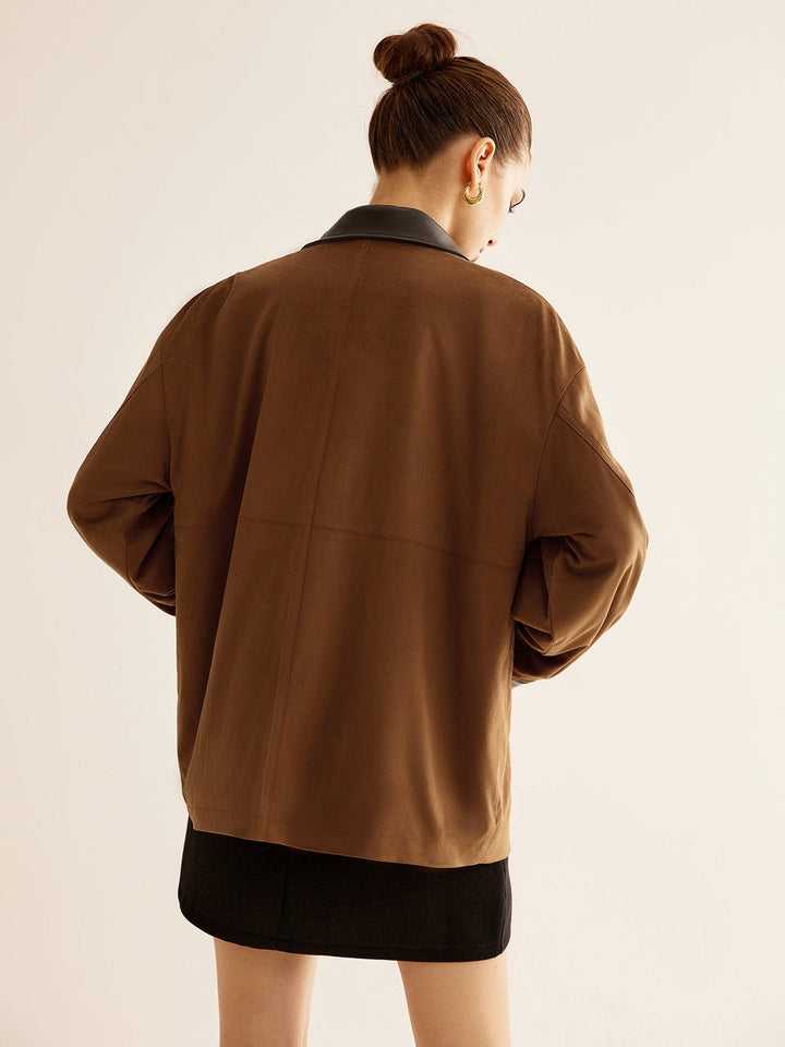 Vue arrière d'une veste oversize Tiphaine pour femme, avec un col en cuir noir et une coupe moderne. L'ensemble est complété par une jupe noire, créant un look élégant et tendance.
