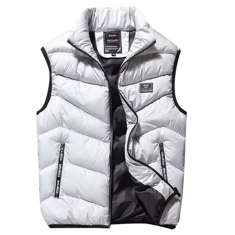 Gilet matelassé pour homme de couleur grise avec fermeture éclair sur le devant et poches zippées. Le modèle présente un col montant pour plus de confort et une doublure intérieure sombre contrastante. Ce vêtement sans manches offre un style moderne et fonctionnel, parfait pour l’hiver ou les journées fraîches en extérieur.