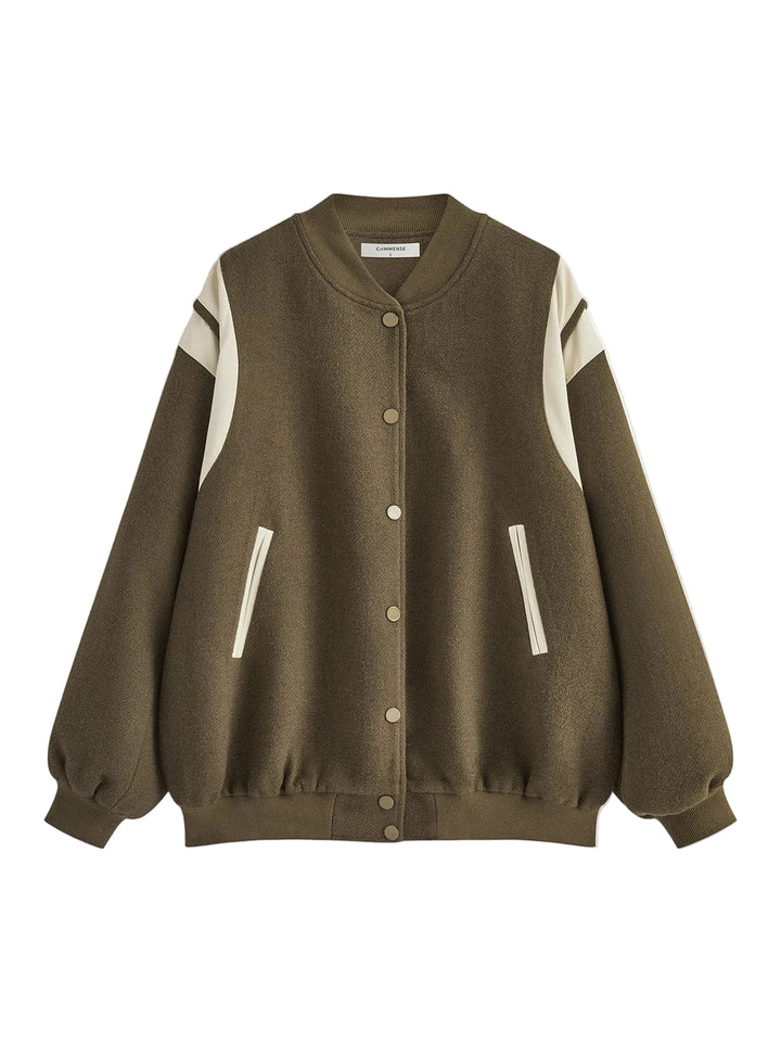 veste en jean bleu foncé avec empiècements crème sur les épaules, fermeture par boutons-pression argentés et poches latérales, coupe légèrement oversize, look tendance en extérieur urbain.