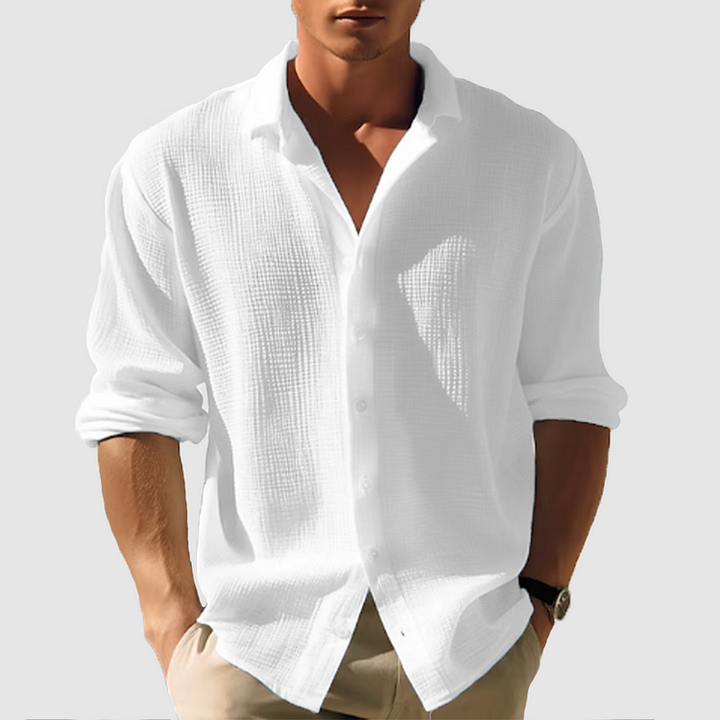 Chemise manches longues Ulysse pour homme, coupe moderne en tissu texturé blanc, portée avec un pantalon beige, manches retroussées, look élégant décontracté.