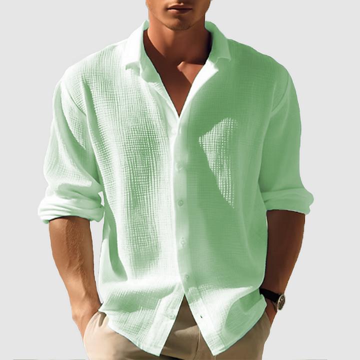 Chemise manches longues Ulysse pour homme, coupe moderne en tissu texturé vert menthe, portée avec un pantalon beige, manches retroussées, look élégant décontracté.