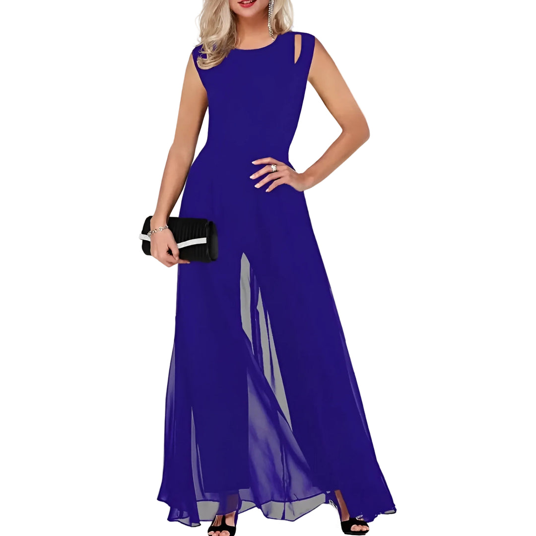 Combinaison d’été Ursuline pour femme, bleu roi style fête, coupe longue fluide avec voile léger et épaules ajourées, portée avec pochette et talons.