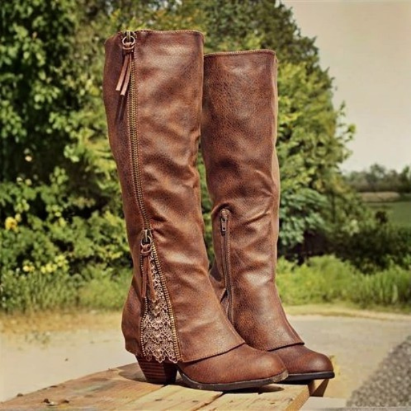 Bottes marron à talon moyen, avec une fermeture éclair décorée de broderies délicates sur le côté. Le cuir vieilli et les détails fins créent un look élégant et moderne, inspiré du style western.
