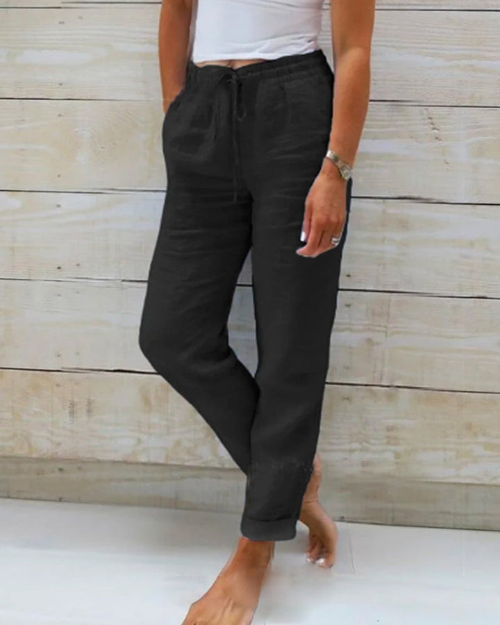 Un pantalon élégant et confortable pour femme, de couleur noire, avec un cordon de serrage à la taille et une coupe décontractée, offrant un look moderne et pratique.