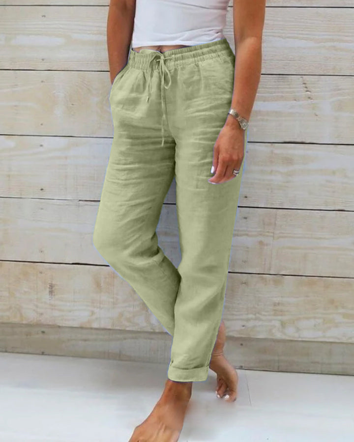 Un pantalon léger et élégant pour femme, de couleur vert pâle, avec un cordon de serrage à la taille et une coupe décontractée, parfait pour une tenue moderne et confortable.