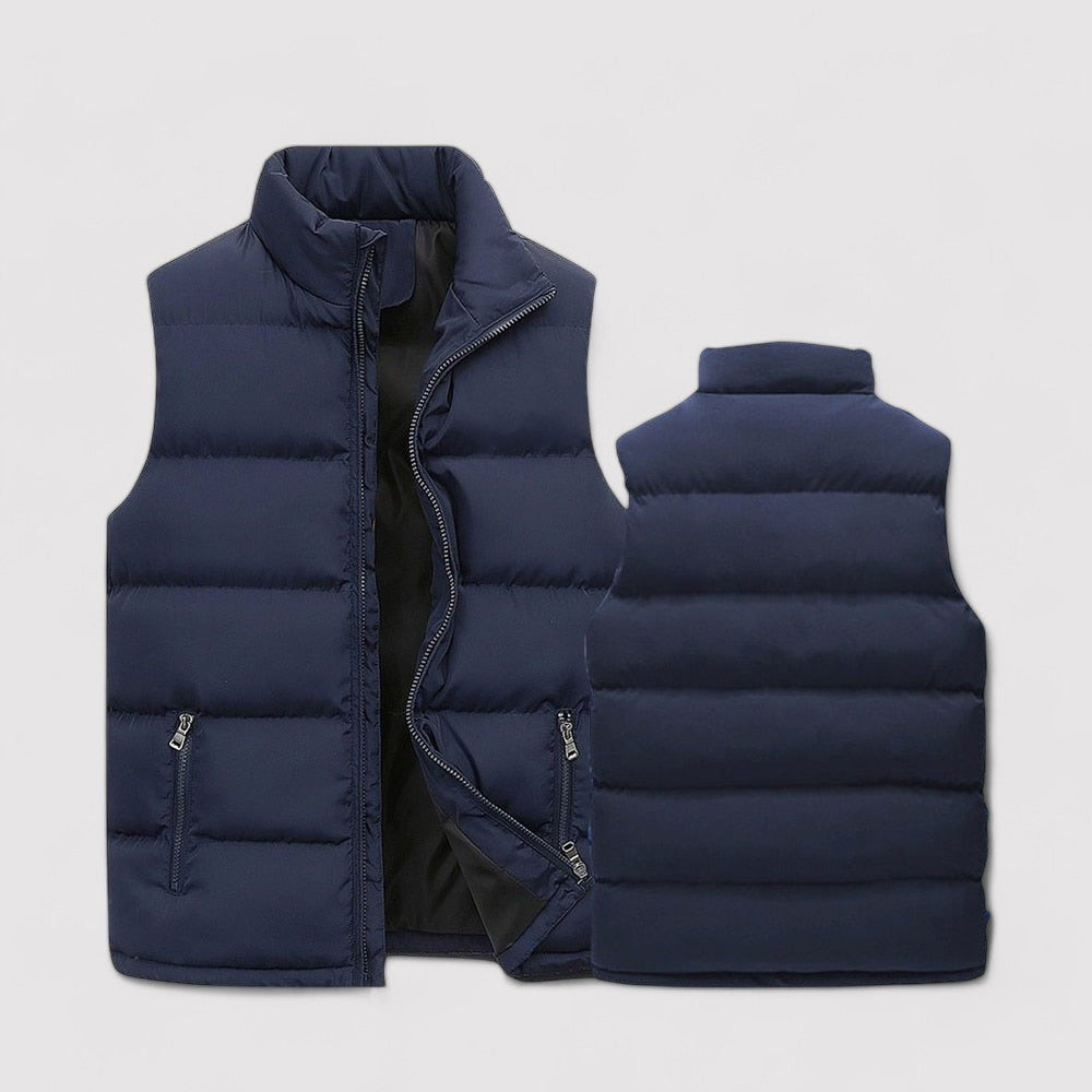 Gilet sans manches bleu marine pour homme, matelassé avec des poches latérales zippées et un col montant. Ce gilet est parfait pour apporter chaleur et confort pendant les journées fraîches.