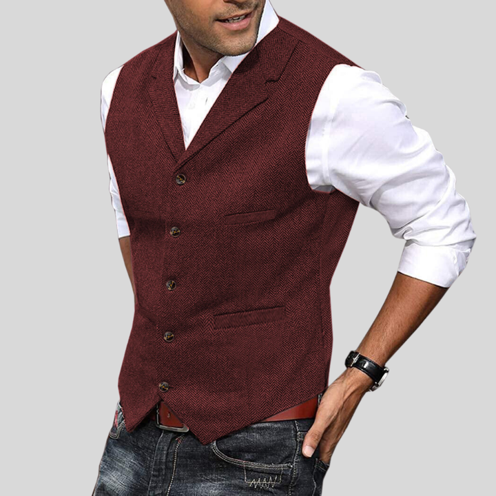 Gilet court pour hommes Virgile moderne, vert foncé à motif chevrons, coupe ajustée avec boutons et poches, porté sur chemise blanche avec jean.