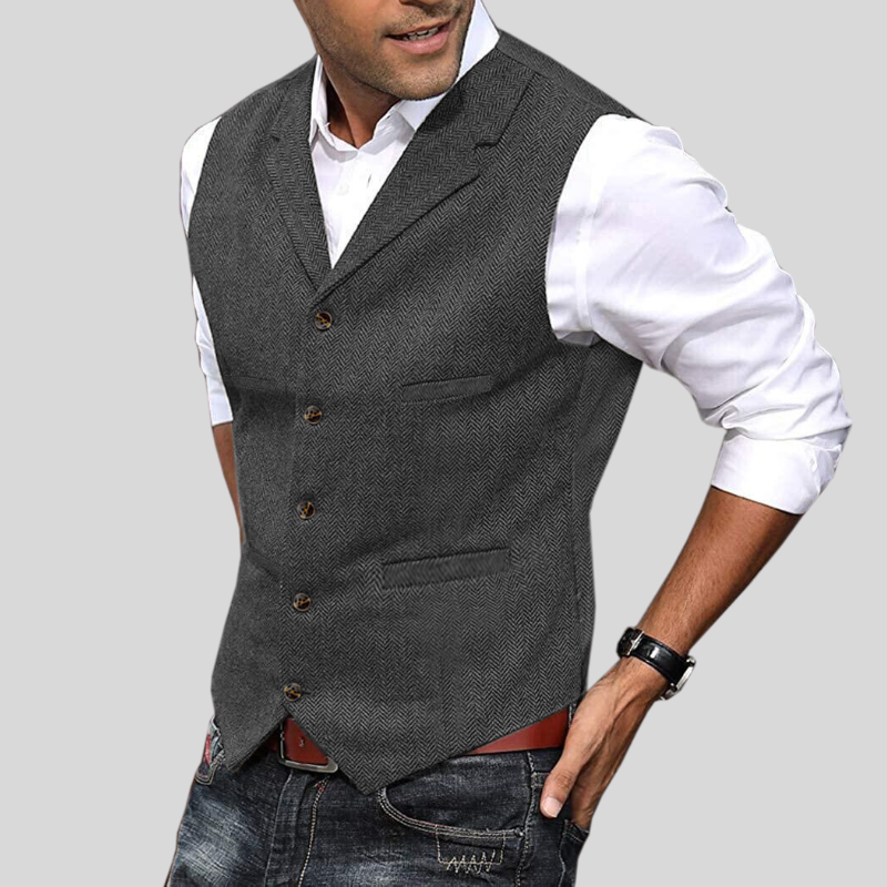 Gilet court pour hommes Virgile moderne, gris anthracite à motif chevrons, coupe ajustée avec boutons et poches, porté sur chemise blanche avec jean.