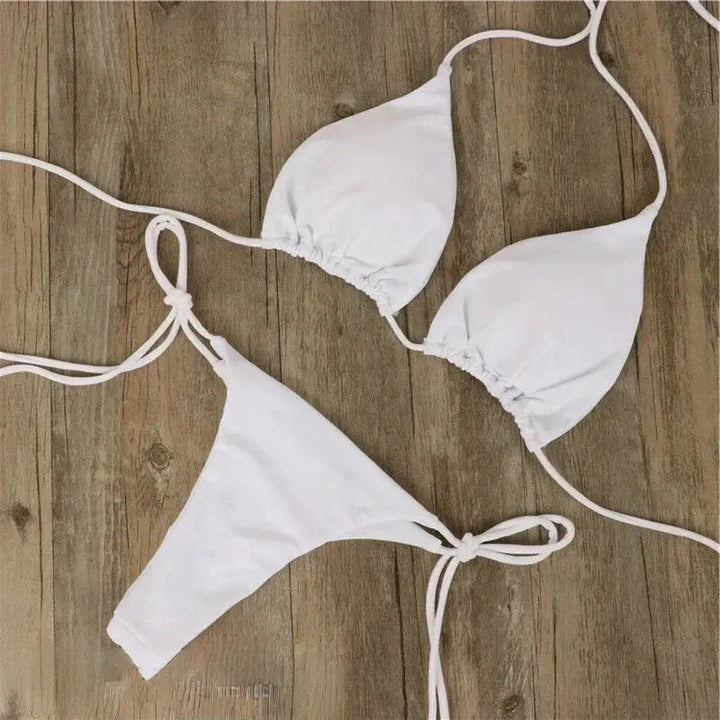 Ensemble bikini femme Virginie moderne de couleur blanche, composé d’un haut triangle à liens ajustables et d’un bas à nouer sur les côtés, présenté à plat sur fond en bois pour un style minimaliste et élégant.