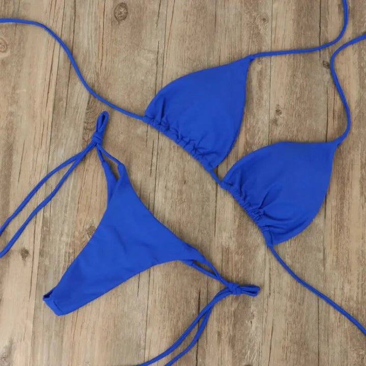 Ensemble bikini femme Virginie moderne de couleur bleu vif, composé d’un haut triangle à liens ajustables et d’un bas à nouer sur les côtés, présenté à plat sur fond en bois pour un style tendance et épuré.