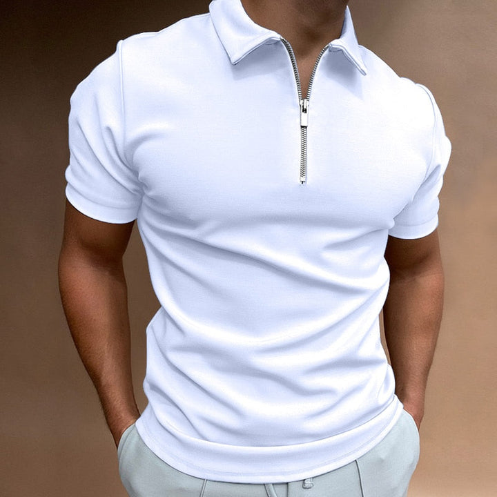 Polo pour homme blanc à manches courtes, coupe ajustée et moderne, avec col structuré et fermeture zippée, porté avec un pantalon clair pour un style élégant, minimaliste et contemporain.