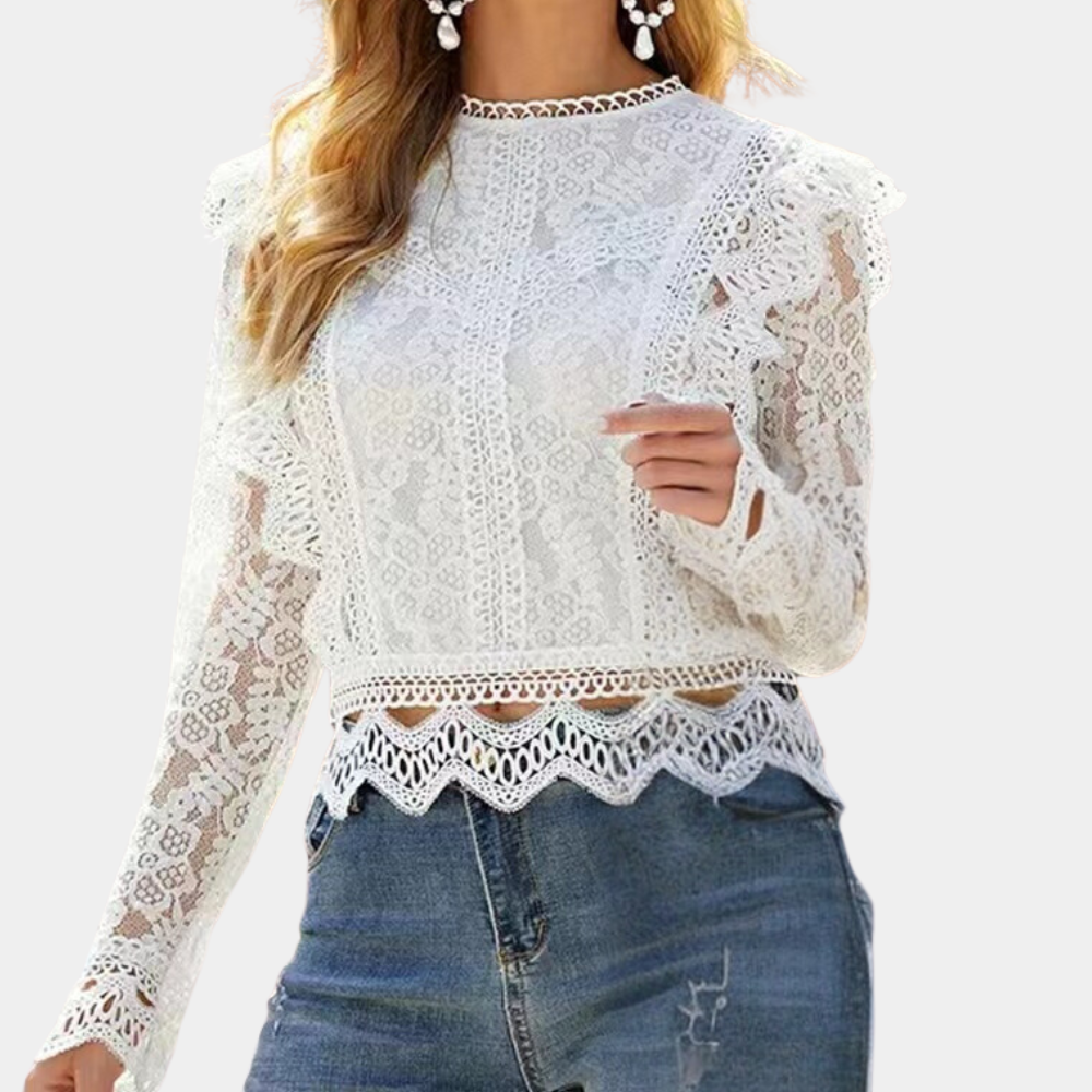 Chemisier en dentelle blanche à manches longues, avec des détails raffinés en dentelle sur les bords et des manches légèrement évasées. Il est porté avec un jean, créant un look moderne et élégant, parfait pour une tenue à la fois chic et décontractée.