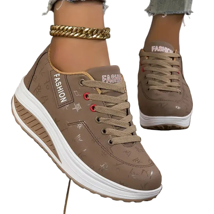 Chaussures plates pour femme Wanda tendance, baskets basses taupe à lacets avec détails, semelle épaisse blanche antidérapante, portées sur fond blanc.