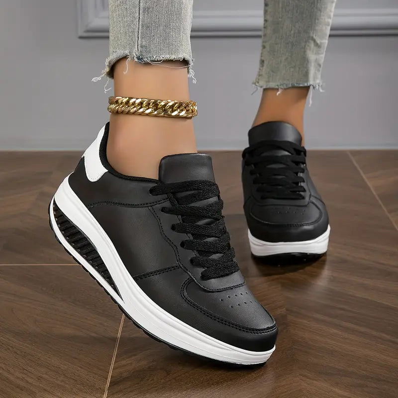 Chaussures plates pour femme Wanda tendance, baskets basses blanches à lacets avec semelle épaisse confortable et antidérapante, portées avec un jean sur sol en bois.