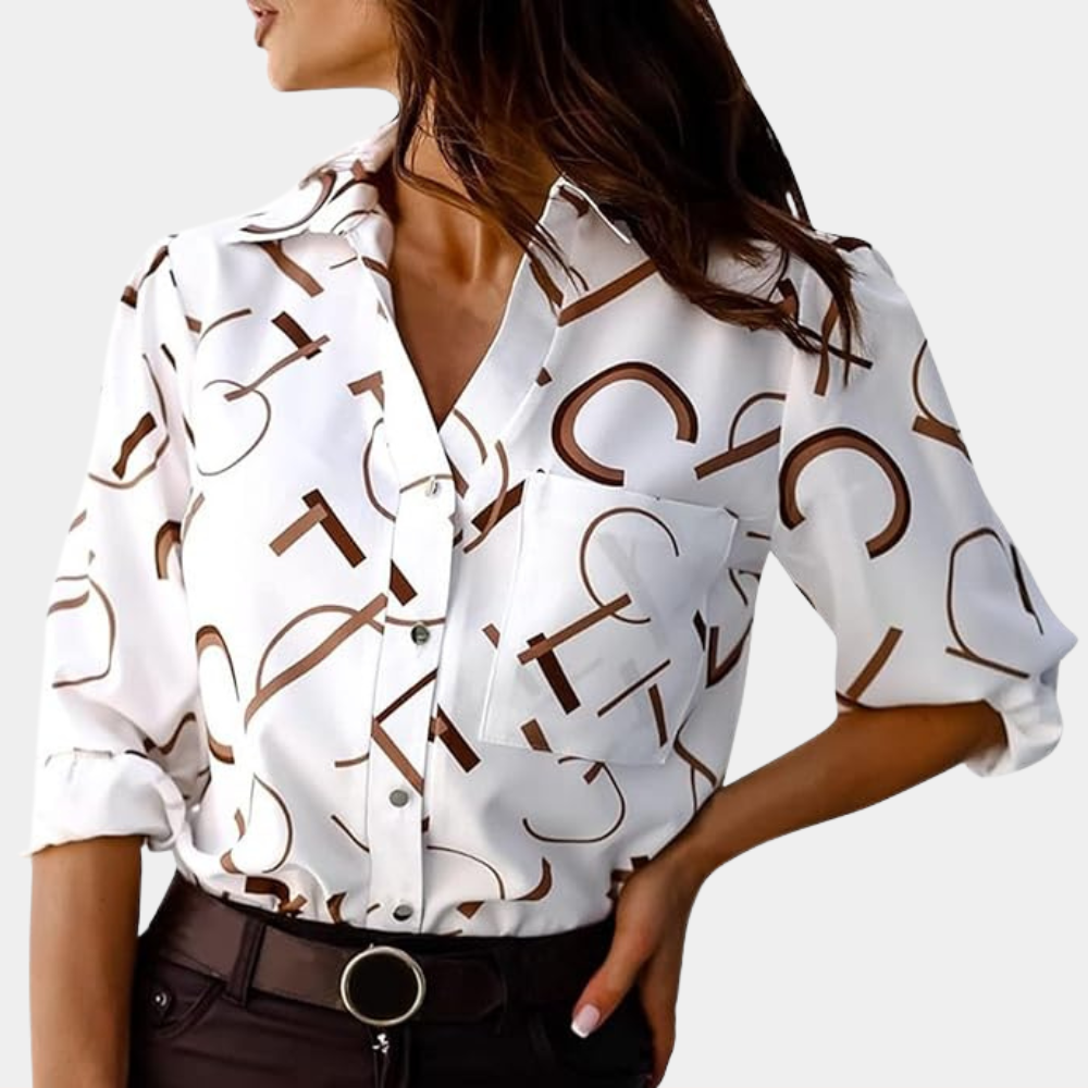 Chemise femme Xavine blanche à lettres graphiques marron portée avec un pantalon foncé. Modèle avec col classique, poche poitrine et manches retroussées, idéal pour un look tendance, moderne et élégant.