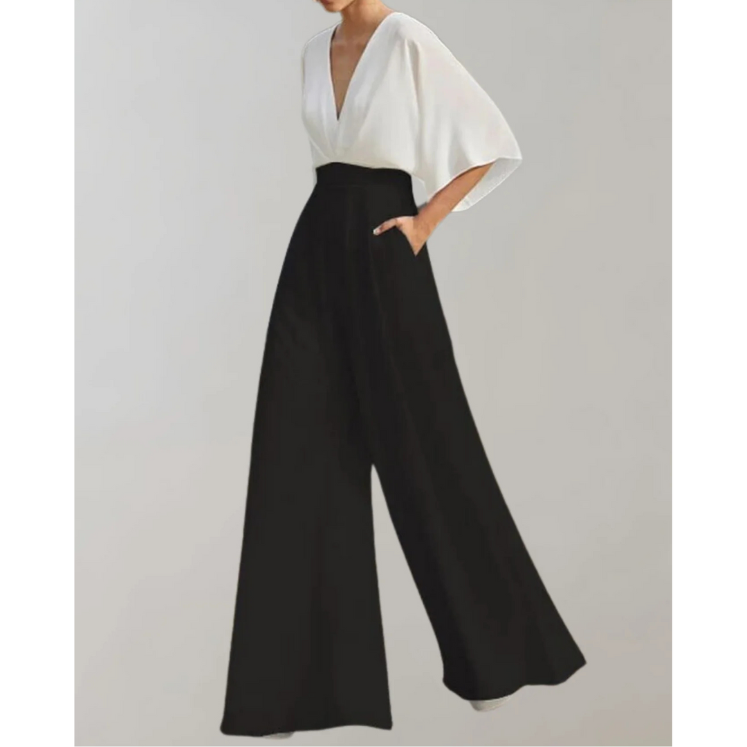 Combinaison bicolore blanc et noir à col V, manches amples, taille haute marquée et pantalon large, portée par un mannequin sur fond neutre.