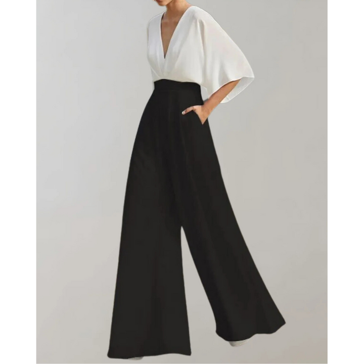 Combinaison bicolore blanc et noir à col V, manches amples, taille haute marquée et pantalon large, portée par un mannequin sur fond neutre.