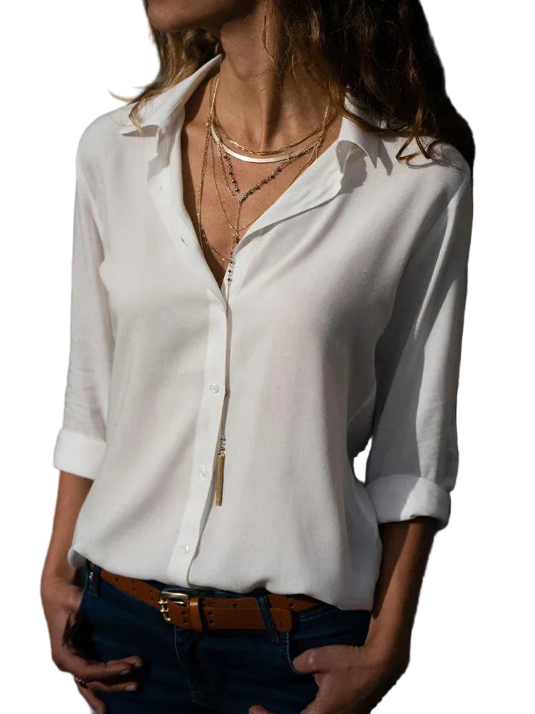 Femme portant la blouse Yvette tendance à manches longues, blanche et fluide avec col ouvert et boutons, associée à un jean et des bijoux dorés pour un look chic.