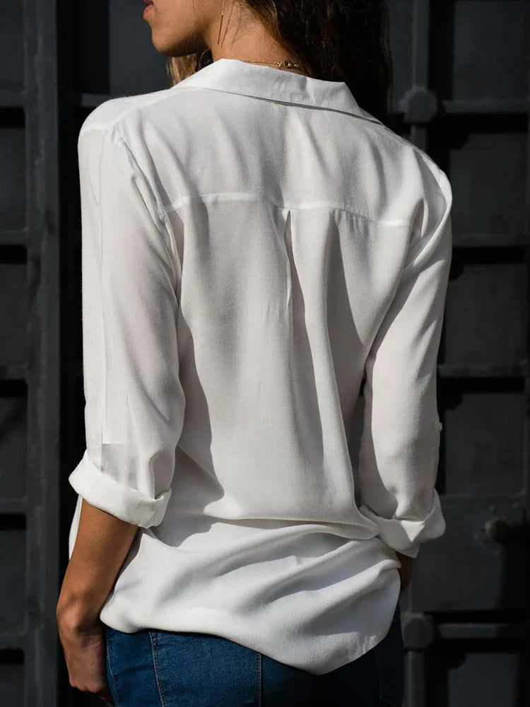 Vue arrière de la blouse Yvette tendance à manches longues, blanche et fluide avec col chemise et plis au dos, portée avec un jean pour un style élégant au quotidien.