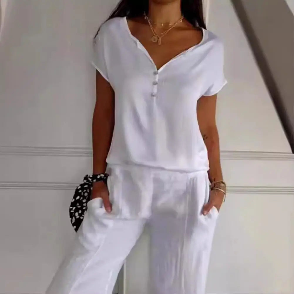 Haut blanc à manches courtes avec un décolleté en V et des boutons délicats, porté avec un pantalon ample assorti. Ce look chic et décontracté est complété par un accessoire élégant au poignet, parfait pour un style moderne et confortable.
