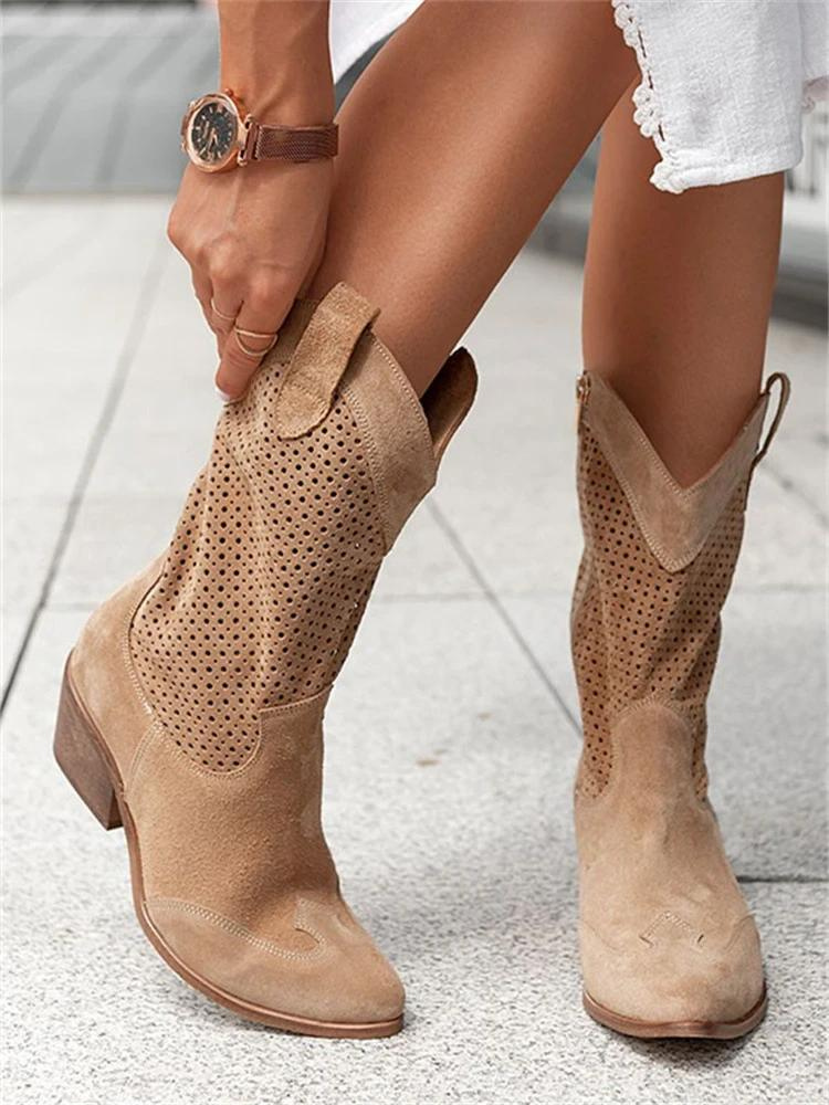 Une paire de bottes western mi-hautes en daim beige clair, dotées de découpes perforées et d’un petit talon en bois. Le design associe élégance et confort, idéal pour un look bohème ou décontracté. Les bottes sont portées avec une robe blanche légère, soulignant un style estival chic et tendance.