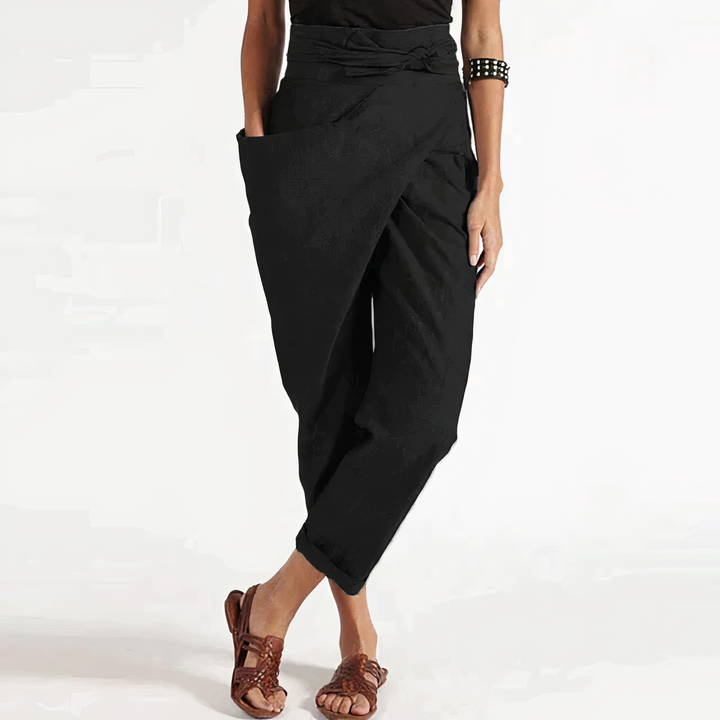 Pantalon d’été Zorine pour femme, noir style sarouel avec taille nouée et coupe ample, porté avec sandales, look tendance et confortable.